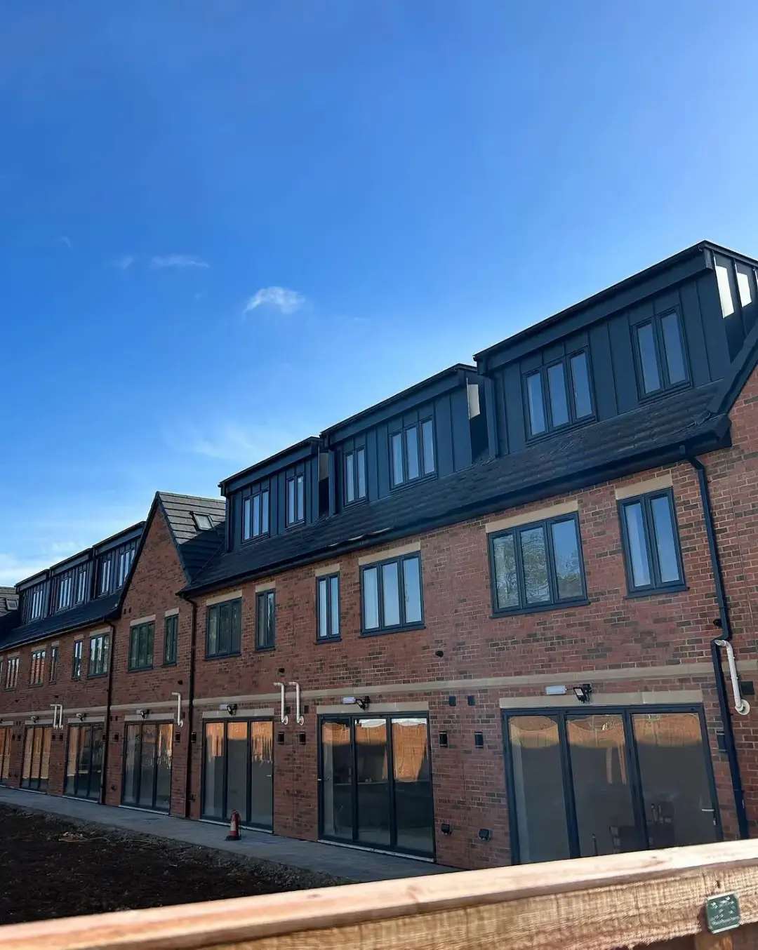 Dark standing seam dormers above a row of brick houses